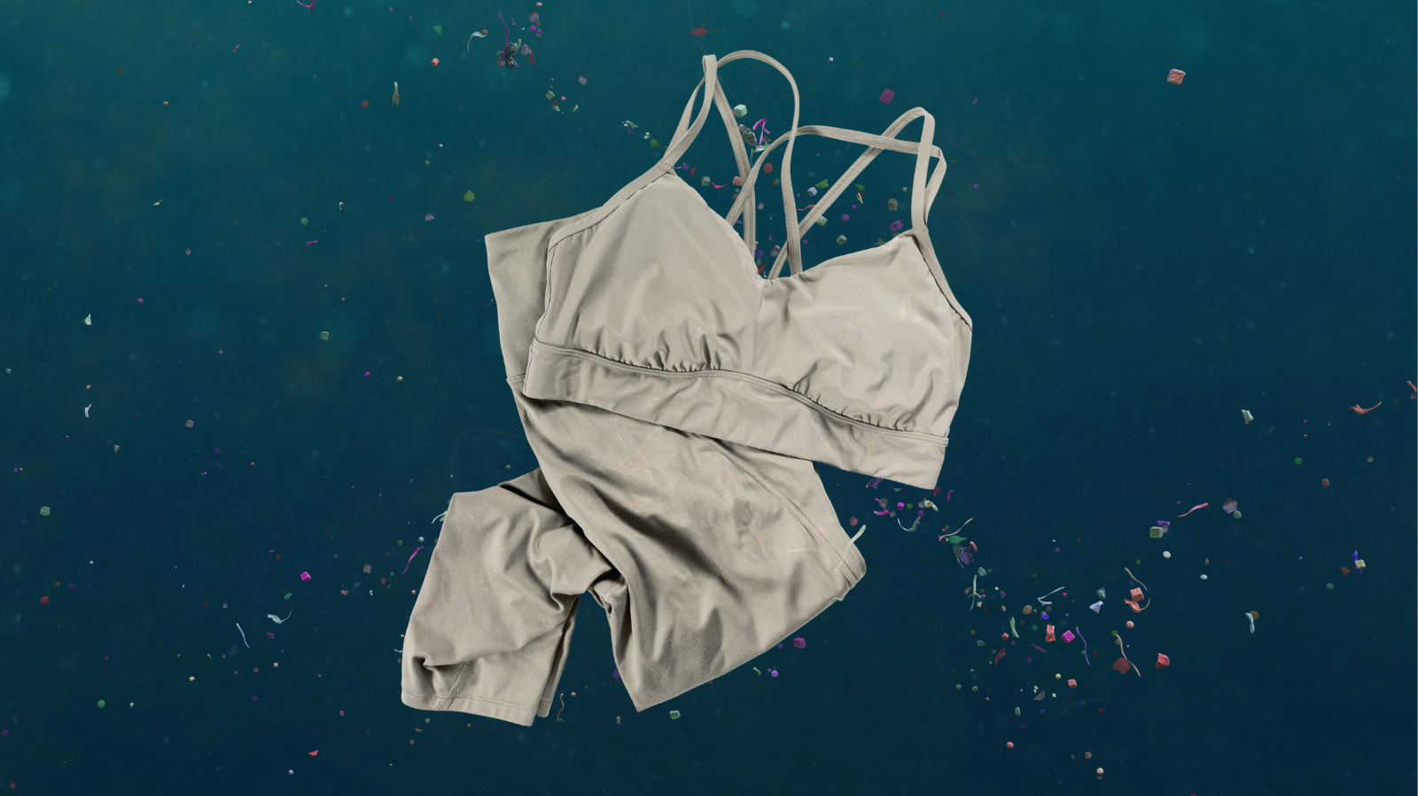 Grey activewear set floating in dark water surrounded by microplastic particles.