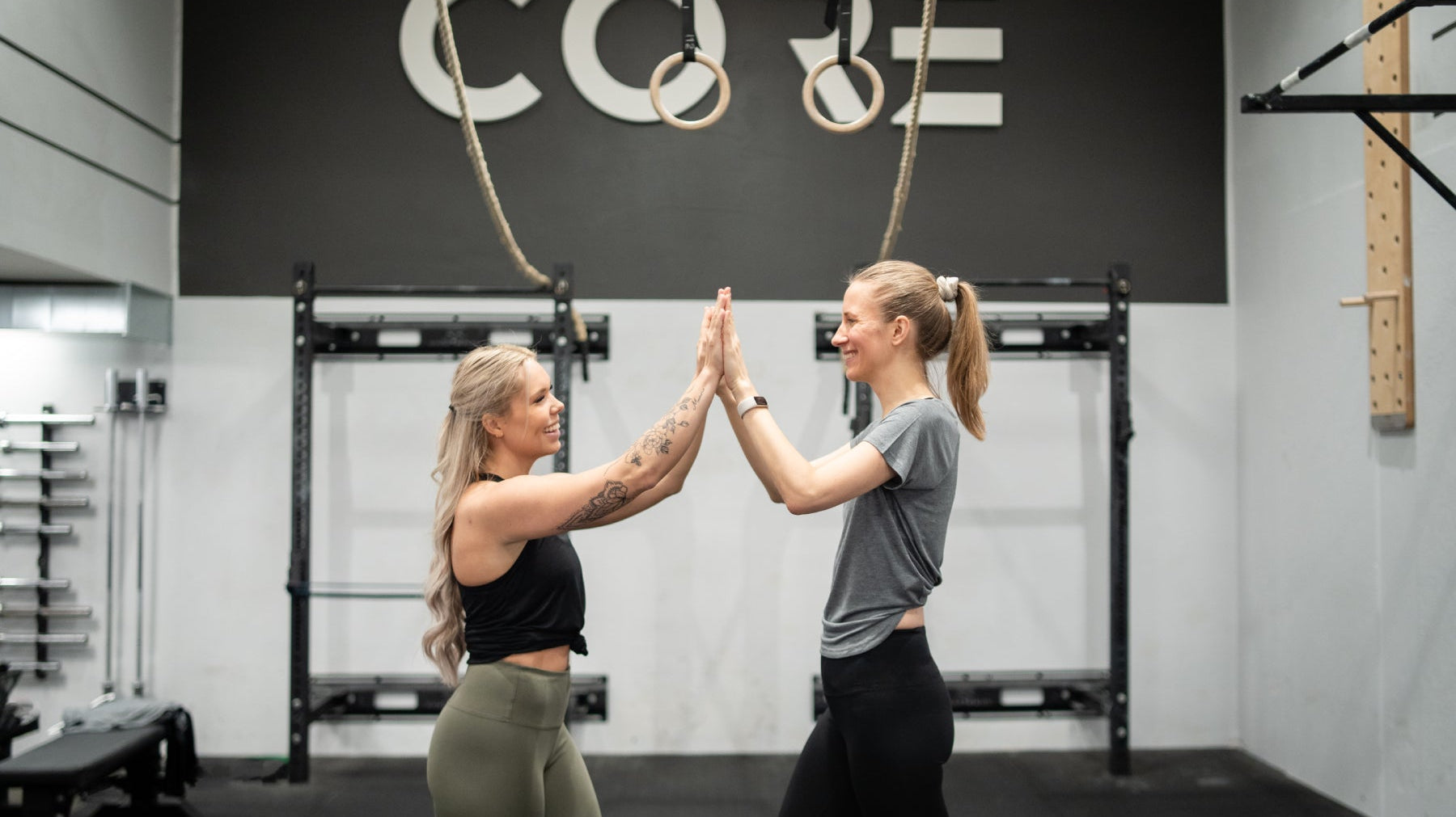 Two women high-fiving in a gym in Tripulse activewear.