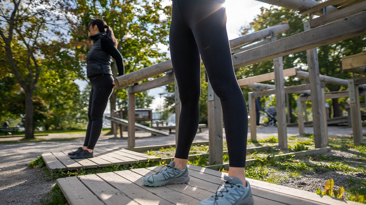 Close-up of legs in black TENCEL leggings climbing wooden outdoor steps.