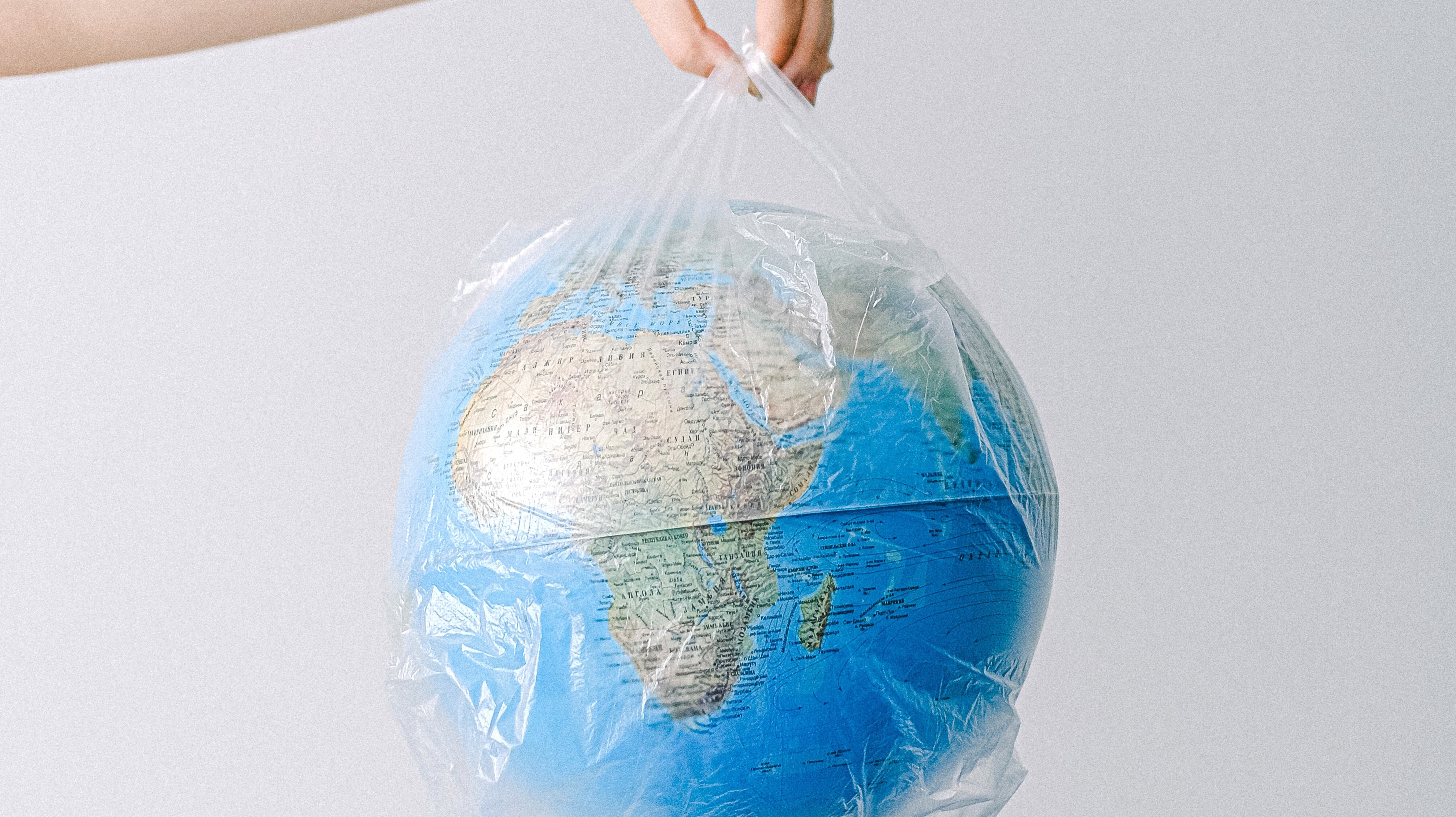Hand holding a small globe wrapped in a plastic bag.