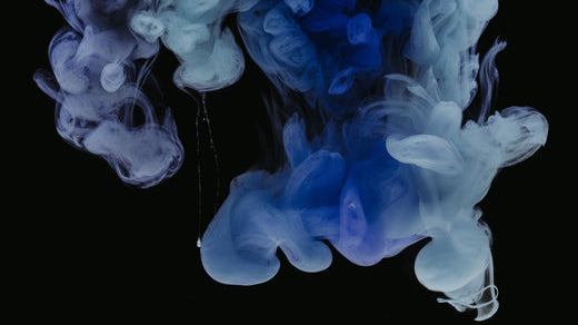 Blue and white ink clouds swirling in dark water.