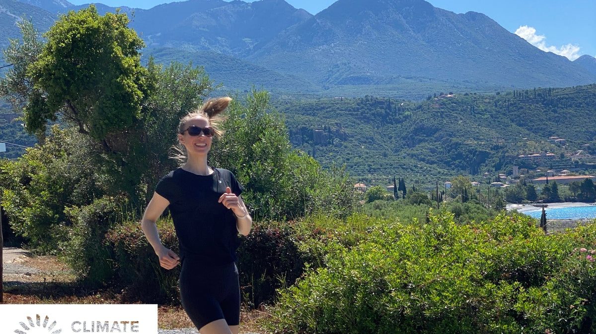 Woman running on a sunny mountain trail with the Climate Neutral Certified label.