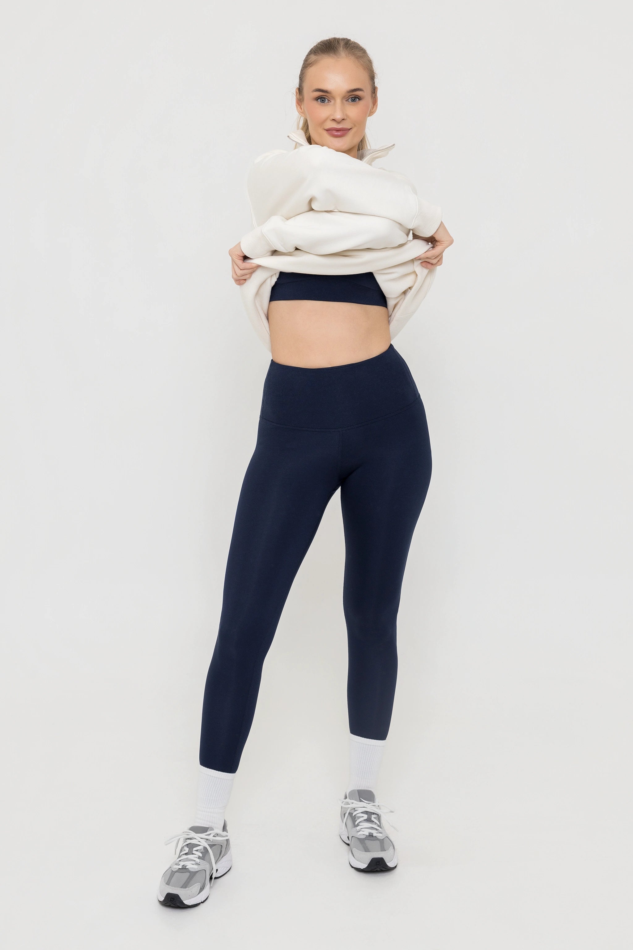 Woman wearing Tencel sports sports bra and leggings in midnight navy with cream sweatshirt