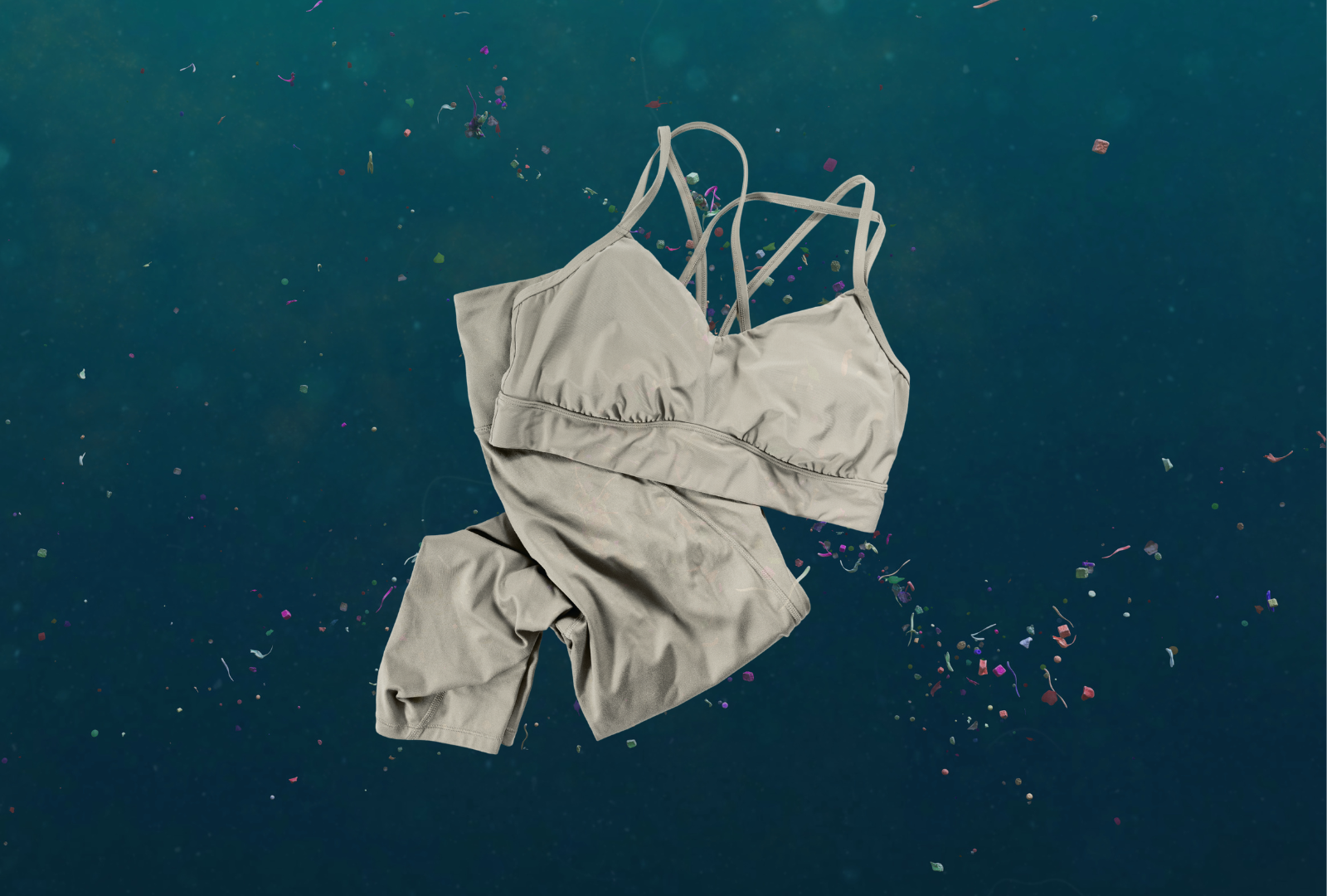 Grey activewear set floating in dark water surrounded by microplastic particles.