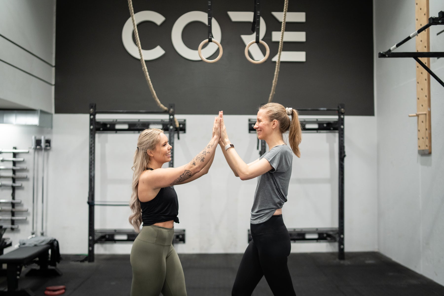 Two women high-fiving in a gym in Tripulse activewear.