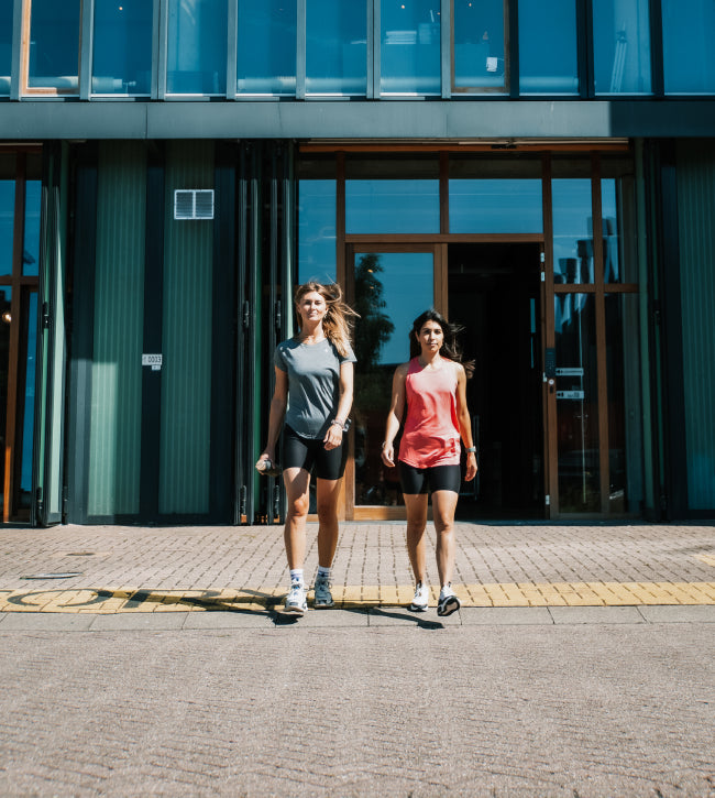 Two women walking out of the factory entrance in Tripulse activewear.