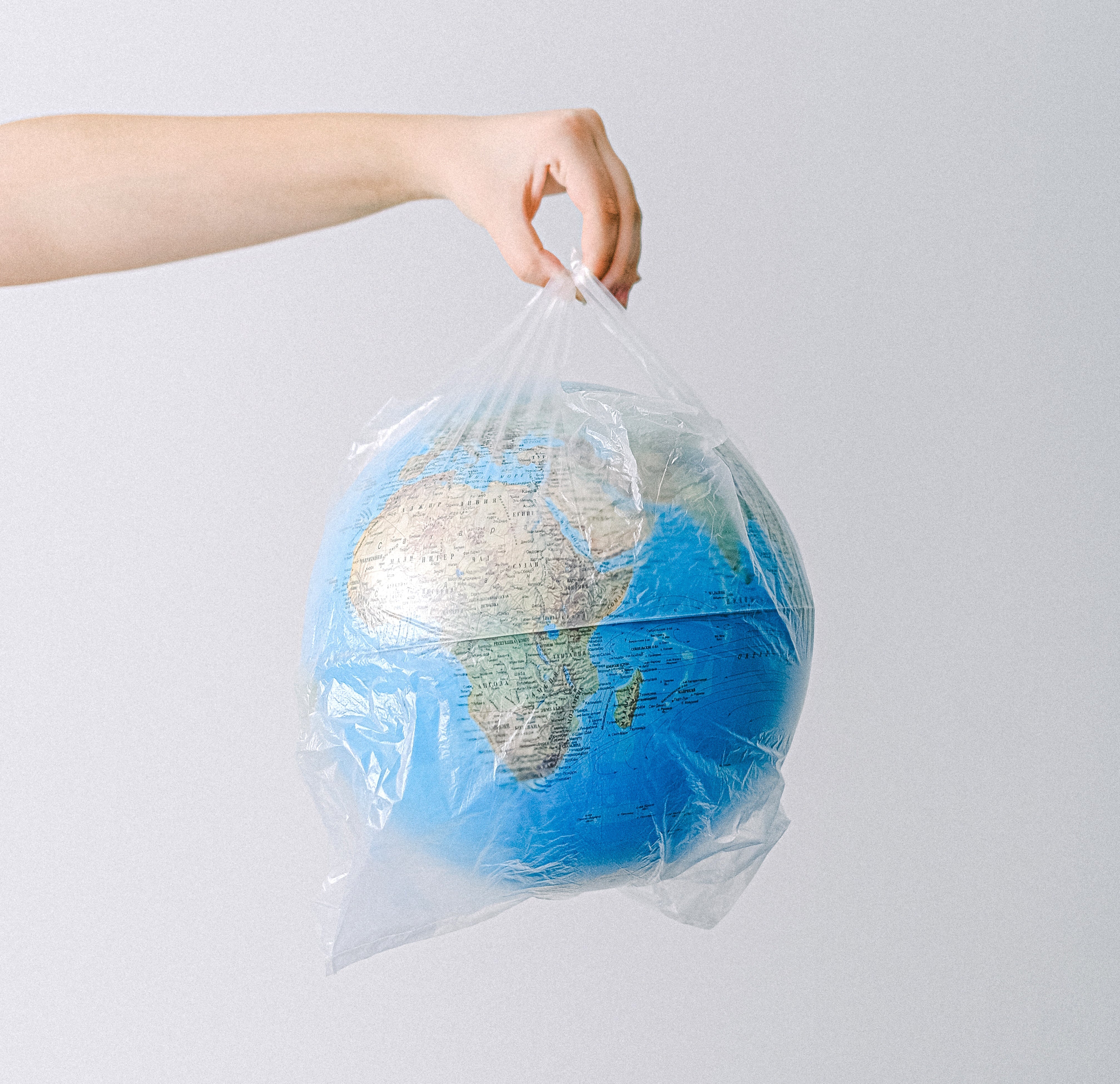 Hand holding a small globe wrapped in a plastic bag.