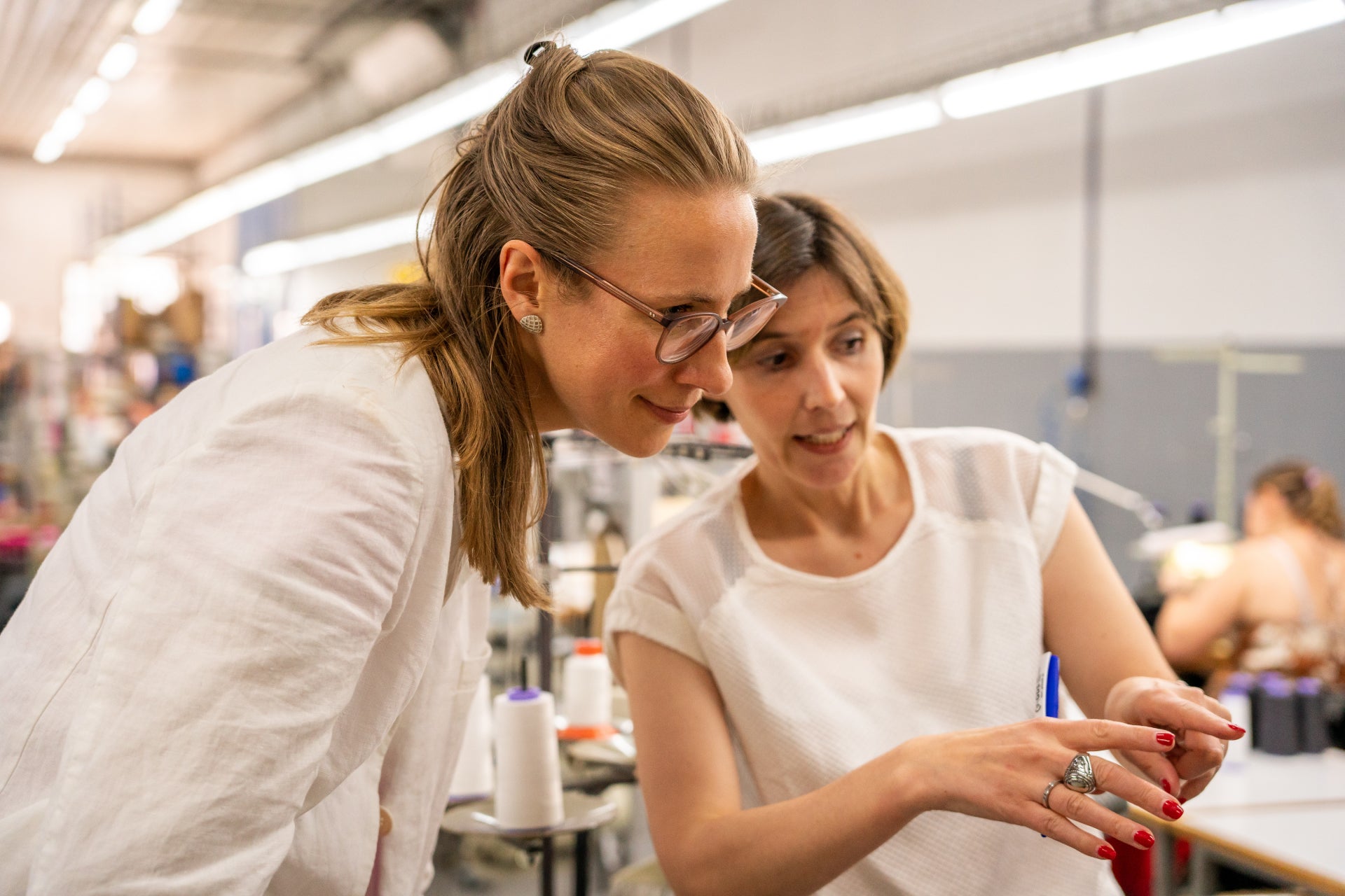 Franziska reviewing garment details with a seamstress in the factory.