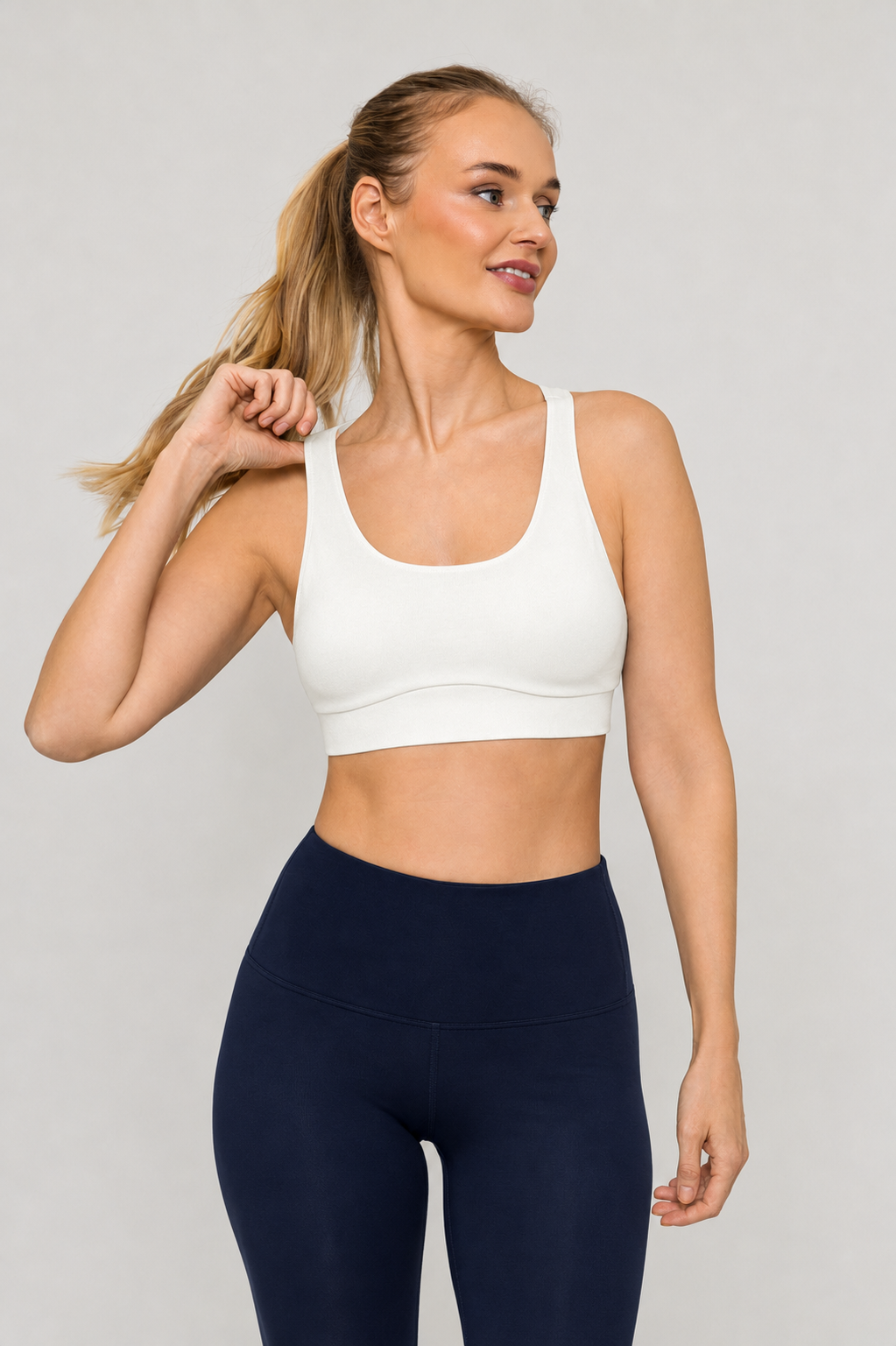 A woman wearing tripulse sports bra in natural white and navy leggings